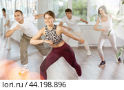 Happy young girl in sportswear with group active people practising twist or charleston dancing in dance hall. Стоковое фото, фотограф Яков Филимонов / Фотобанк Лори