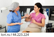 Plastic surgeon and woman discussing procedure of breast augmentation during consultation. Стоковое фото, фотограф Яков Филимонов / Фотобанк Лори