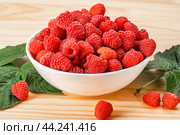Raspberries on white plate on wooden table with leaves. Organic raspberries grown without use of chemical fertilizers and pesticides. Raspberries on wooden background. Стоковое фото, фотограф Павел Муравьев / Фотобанк Лори