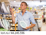 Man choosing plates in store. Стоковое фото, фотограф Яков Филимонов / Фотобанк Лори