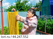 Женщина развешивает на открытом воздухе сушиться постиранное бельё. Стоковое фото, фотограф Александр Бушков / Фотобанк Лори