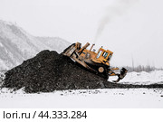 Бульдозер в горной местности сгребает кучу горного золотосодержащего грунта , который в дальнейшем будет перевозиться на промывку с целью извлечения желтого драгоценного метала. Стоковое фото, фотограф Павел Просянов / Фотобанк Лори