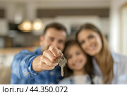 Homeowners. Happy young Caucasian family spouses standing indoors holding car house flat apartment keys, celebrating new purchase buying real estate. Mortgage loan. New home. Mother, father and child. Стоковое AI-изображение, AI-художник Марина Демидюк / Фотобанк Лори