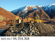 Фронтальный колесный погрузчик Komatsu WA500 высыпает на промывку горный золотосодержащий грунт, в бункер промывочной машины. Республика САХА, ЯКУТИЯ, Оймяконский район. (2009 год). Редакционное фото, фотограф Павел Просянов / Фотобанк Лори