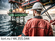 Oil production. An oil well and a man in work clothes and a construction helmet. Oil platform and industrial equipment. Difficult working conditions. Стоковое AI-изображение, AI-художник Photojuli / Фотобанк Лори