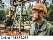 Oil production. An oil well and a man in work clothes and a construction helmet. Oil platform and industrial equipment. Difficult working conditions. Стоковое AI-изображение, AI-художник Photojuli / Фотобанк Лори