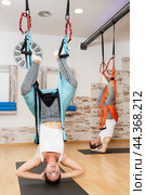 Girl performing inverted butterfly pose in hammock at aerial pilates training. Стоковое фото, фотограф Яков Филимонов / Фотобанк Лори