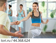 Couple in comfortable sports clothes learns boogie woogie dancing during individual lesson. Стоковое фото, фотограф Яков Филимонов / Фотобанк Лори