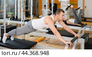 Man in different poses performs static and dynamic exercises on reformer. Стоковое фото, фотограф Яков Филимонов / Фотобанк Лори