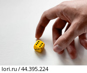 Hand reaching for yellow dice on white background - symbol of chance and decision. Стоковое фото, фотограф Lamina Akulova / Фотобанк Лори