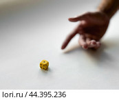 Hand preparing to roll yellow dice on minimalist white background. Стоковое фото, фотограф Lamina Akulova / Фотобанк Лори