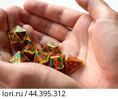 Colorful dungeons and dragons dice set held in hands for tabletop gaming enthusiasts. Стоковое фото, фотограф Lamina Akulova / Фотобанк Лори