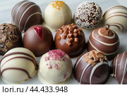 Assorted gourmet chocolate truffles on display. Стоковое AI-изображение, AI-художник Иван Рябоконь / Фотобанк Лори