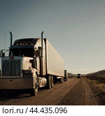 Crosscountry trucking adventure across vast landscapes with a truck in the foreground on an open highway surrounded by mountains and blue skies. Generative AI. Стоковое AI-изображение, AI-художник Юлия Петровская / Фотобанк Лори