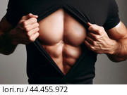 Руки мужчины отодвигают края черной рубашки, демонстрируя накачанные мышцы спортивного мужского тела. Мужской торс, крупный план. Стоковое AI-изображение, AI-художник Sergei Gorin / Фотобанк Лори