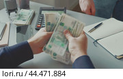 Person exchanging cash at a desk while calculating expenses with a calculator in a business setting. Стоковое видео, видеограф Сергей Толмачёв / Фотобанк Лори