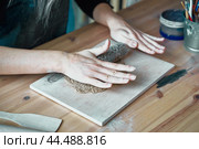 Woman making pattern on ceramic plate, hands close-up, focus on palms. Стоковое фото, фотограф Natalia Gdovskaia / Фотобанк Лори