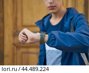 Young adult looks at the clock, waiting for a meeting with friends. A man is waiting for a woman in a street of city on a date, looking at the watch. Стоковое фото, фотограф Natalia Gdovskaia / Фотобанк Лори