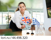 Young lady sets miniatures of flags of Greece and Great Britain before international negotiations. Стоковое фото, фотограф Яков Филимонов / Фотобанк Лори