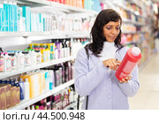 Hispanic woman choosing hair care treatments in cosmetics store. Стоковое фото, фотограф Яков Филимонов / Фотобанк Лори