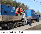 Industrial generators on cargo trucks with "SDMO" and "MSK energo" logos parked on roadside with workers. Equipment transport - Moscow, Russia, March 20, 2023. Редакционное фото, фотограф Андрей Журавлев / Фотобанк Лори