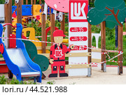 Children's playground with colorful play structures and a toy gas station. Lukoil-themed decor with wooden elements and slide. Outdoor activity and play concept - Moscow, Russia, March 20, 2021. Редакционное фото, фотограф Андрей Журавлев / Фотобанк Лори