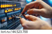 Network technician plugging ethernet cable into server in datacenter. Стоковое AI-изображение, AI-художник Юрий Поздников / Фотобанк Лори