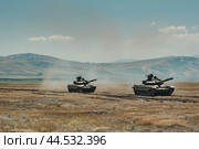 Military tanks maneuvering in desert terrain. Стоковое AI-изображение, AI-художник Иван Рябоконь / Фотобанк Лори