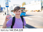 Школьник держит социальную льготную карту Учащегося Москвича на остановке в ожидании автобуса. Редакционное фото, фотограф Яна Проничева / Фотобанк Лори