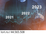Economic recovery after falling due to inflation, stagnation, recession, 2024 financial chart. Businessman pointing graph of future growth on dark blue background. Стоковое фото, фотограф Павел Муравьев / Фотобанк Лори