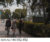 Three female students walk along the university building. KIMEP at the intersection of Abai and Dostyk Avenues. Kazakhstan. Alma-Ata. 25.08.2024. Редакционное фото, фотограф Ярославский Максим / Фотобанк Лори