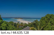 Beautiful postcard tropical landscape. A sandbar winds towards a small island. The boats are anchored in the aquamarine ocean. Silhouettes of people on the beach. In the foreground is lush vegetation. Стоковое фото, фотограф Вера Ивановна Кубарева / Фотобанк Лори