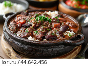 Brazilian feijoada in a traditional clay pot. Стоковое AI-изображение, AI-художник Иван Рябоконь / Фотобанк Лори