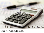 Calculator lying on a spreadsheet with a pen out of focus in the background. Стоковое AI-изображение, AI-художник Иван Рябоконь / Фотобанк Лори