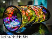 Flexible display showing flowers is illuminated at a technology exhibition. Стоковое AI-изображение, AI-художник Иван Рябоконь / Фотобанк Лори