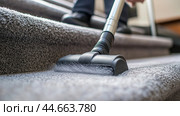 Person vacuuming a carpeted staircase to maintain cleanliness in a residential home during daylight hours. Стоковое AI-изображение, AI-художник Сергей Толмачёв / Фотобанк Лори