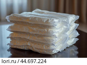 Stack of adult diapers resting on a table. Стоковое AI-изображение, AI-художник Иван Рябоконь / Фотобанк Лори