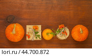 Autumn composition with pumpkins, marigolds and handmade gifts in paper gift boxes on old wooden background. Congratulations on autumn holiday, Thanksgiving, Halloween or beginning of autumn. Стоковое фото, фотограф Виктория Катьянова / Фотобанк Лори