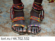 Woman wearing traditional beaded jewelry and sandals standing on dirt road. Стоковое AI-изображение, AI-художник Иван Рябоконь / Фотобанк Лори