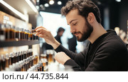 Young man exploring scent options in a modern fragrance store during the day. Стоковое AI-изображение, AI-художник Сергей Толмачёв / Фотобанк Лори