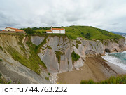 Charming Zumaia Itzurun beach. Steeply-tilted layers of flysch. Atlantic ocean surf and lonely house in Basque Autonomous Community  in day in Bay of Biscay. View from above / top view. Стоковое фото, фотограф YuryKara / Фотобанк Лори