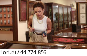Woman with phone in hands walks around hall of museum, examines showpiece at exhibition. Стоковое видео, видеограф Яков Филимонов / Фотобанк Лори