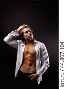 Portrait of stylish guy fashion model in unbuttoned white shirt with abs muscle press posing in shadow, looking up. Stylish man with perfect muscular sexy torso, black studio shot. Copy ad text space. Стоковое фото, фотограф Aleksandr Golubev / Фотобанк Лори
