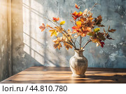 Branches with golden autumn leaves in a ceramic vase on a wooden table by the window. The concept of home comfort. Autumn decor for Halloween. Стоковое AI-изображение, AI-художник Photojuli / Фотобанк Лори