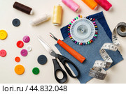 Sewing supplies and denim fabric arranged on a workspace for clothing alterations in a bright setting. Стоковое фото, фотограф Сергей Толмачёв / Фотобанк Лори