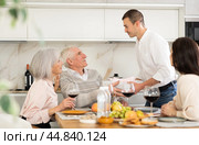 Birthday senior man accepts outright gift and greetings from adult son during family feast. Стоковое фото, фотограф Яков Филимонов / Фотобанк Лори