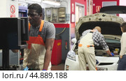 Mechanic and assistant working at auto service. Стоковое видео, видеограф Яков Филимонов / Фотобанк Лори