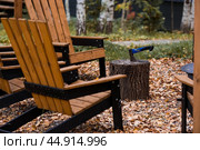 Eco-friendly, stylish barbecue area and wooden chairs for relaxing by the campfire. An axe will be stuck into a wooden log. Chopping firewood. Стоковое фото, фотограф Photojuli / Фотобанк Лори