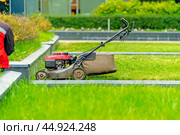 A worker sits next to a lawn mower and does not work. Стоковое фото, фотограф Татьяна Степанищева / Фотобанк Лори
