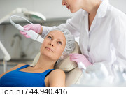 Adult woman on cosmetic procedure in beauty center. Hardware cosmetology. Medical salon procedures of soften skin keratin and deep clear skin dirt. Стоковое фото, фотограф Яков Филимонов / Фотобанк Лори